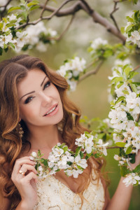 Puffy eyes, relief, Springtime, Spring mood, a beautiful young brunette woman with long curly hair, wearing a white wedding dress, beautiful smile and light make-up, enjoying the beauty of blooming spring garden