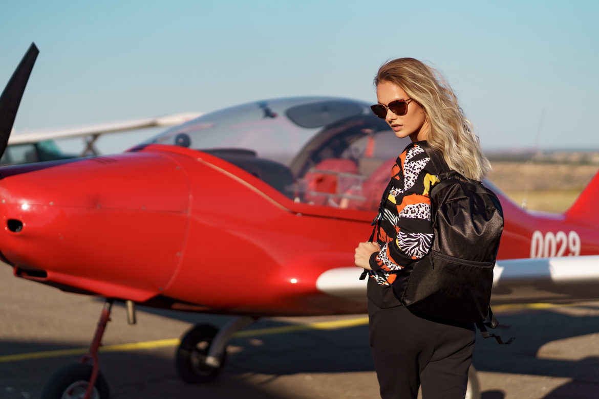 Young,Woman,Model flying private plane,With,A,Modern,Haircut,And,Fashionable,Sunglasses
